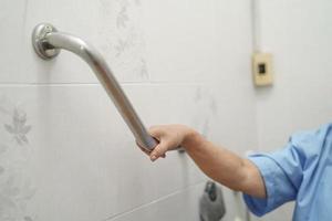 donna anziana asiatica paziente usa la sicurezza della maniglia del bagno della toilette foto