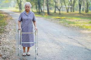 donna anziana asiatica usa il camminatore nel parco.