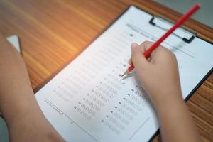 bambini asiatici ragazzino scrivono la risposta in un test d'esame quiz foto