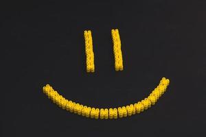 mattoncini di plastica di colore giallo, che formano un sorriso su uno sfondo nero