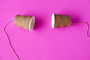 Fai da te carta tazze con corda su rosa sfondo. concetto, telefono giocattoli quale applicare con scienza conoscenza di vibrazione suono attraverso sforzando stringhe causando noi per sentire il suono. foto