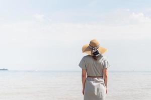 donna in abiti estivi in piedi su un molo, mare sullo sfondo foto