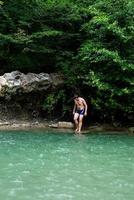 uomo che nuota nel fiume di montagna con una cascata
