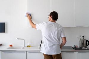 uomo che pulisce le superfici della cucina foto