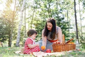 famiglia interrazziale di madre e figlia nel parco che fanno un picnic foto