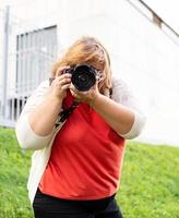 ritratto di donna sovrappeso che scatta foto con una macchina fotografica nel parco