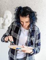 donna creativa con i capelli tinti di blu che dipingono nel suo studio foto