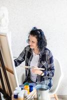 donna creativa con i capelli tinti di blu che dipingono nel suo studio foto