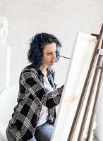 donna creativa con i capelli tinti di blu che dipingono nel suo studio foto