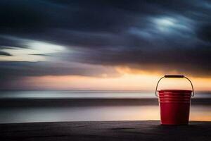 un' rosso secchio si siede su il spiaggia a tramonto. ai-generato foto