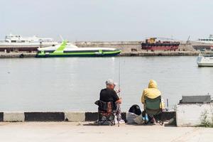 yalta 2021- persone che pescano sull'argine, barche e yacht sullo sfondo foto