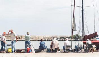 yalta 2021- persone che pescano sull'argine, barche e yacht sullo sfondo