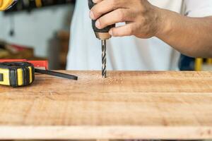 uomo uso cordless trapano o urto autista in un' di legno a costruzione luogo, la lavorazione del legno concetto foto