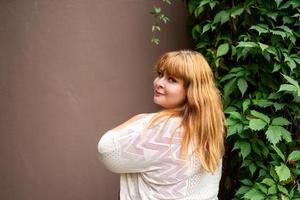 donna sovrappeso in posa sul muro solido marrone sulla strada