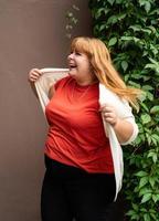 donna sovrappeso in posa sul muro solido marrone sulla strada