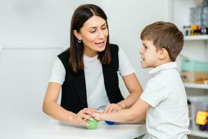 un' donna discorso terapista offerte con il bambino e insegna lui il corretta pronuncia e competente discorso. foto
