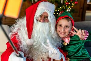 Santa Claus prende un' autoscatto su Natale notte insieme con un' giovane elfo foto