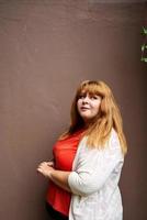 donna sovrappeso in posa sul muro solido marrone sulla strada foto