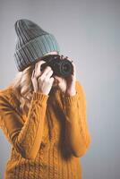 bellissimo ragazza fotografo nel un' a maglia cappello in posa con un' telecamera nel sua mani nel un' foto studio