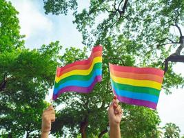 due mani tengono piccole bandiere arcobaleno del movimento lgbtq foto