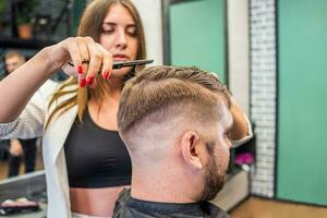 parrucchiere donna fare acconciatura per barbuto uomo nel barbiere foto