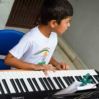 asiatico ragazzo giocando il sintetizzatore o pianoforte. carino poco ragazzo apprendimento Come per giocare pianoforte. del bambino mani su il tastiera interno. foto