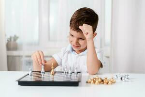 carino ragazzo 5 anni vecchio giochi scacchi di lui stesso nel il suo camera a casa foto