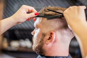 parrucchiere donna fare acconciatura per barbuto uomo nel barbiere foto