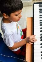 asiatico ragazzo giocando il sintetizzatore o pianoforte. carino poco ragazzo apprendimento Come per giocare pianoforte. del bambino mani su il tastiera interno. foto