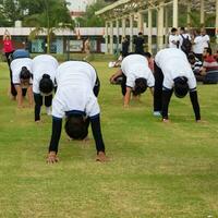 nuovo delhi, India, giugno 21, 2023 - gruppo yoga esercizio sessione per persone a yamuna gli sport complesso nel delhi su internazionale yoga giorno, grande gruppo di adulti frequentando yoga classe nel cricket stadio foto