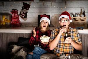 coppia che guarda film a casa a Natale indicando lo schermo foto
