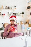 uomo con cappello da Babbo Natale saluta i suoi amici in video chat o chiama su tablet foto