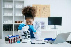 giovane scienziati conduzione ricerca indagini nel un' medico laboratorio, un' ricercatore nel il primo piano è utilizzando un' microscopio nel laboratorio per medicinale. foto