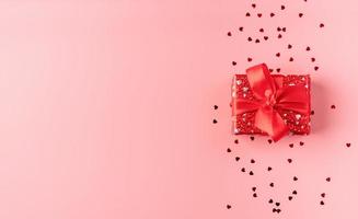 confezione regalo rossa con fiocco in corda su sfondo rosa foto