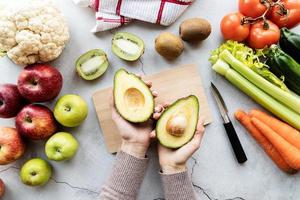 mani femminili che tengono avocado per dieta disintossicante vista dall'alto disteso piatto foto