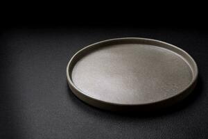 vuoto il giro ceramica piatto su un' buio strutturato sfondo foto