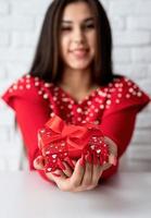 donna in abito rosso con in mano un regalo per san valentino foto