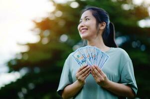 dollaro nel il mani di un asiatico donna risparmio, investimenti, stipendio, reddito, denaro contante fluire, felicità e finanziario successo e investimenti. foto