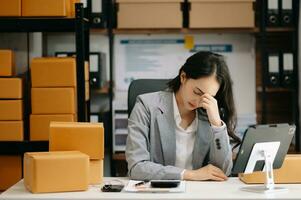 asiatico donna sensazione emicrania testa ceppo.oberato di lavoro donna d'affari finanziere mentre Lavorando su il computer portatile e tavoletta a ufficio. foto