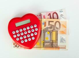 rosso cuore sagomato calcolatrice con Euro banconote. foto