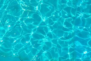 azzurro trasparente struttura di acqua nel un' blu piscina con spruzzi a partire dal il sole foto