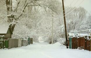 un' rustico inverno paesaggio con alcuni vecchio case e un' ampio autostrada coperto con un' di spessore strato di neve foto