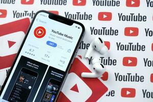 Kharkov, Ucraina - marzo 5, 2021 Youtube musica icona e applicazione a partire dal App memorizzare su i phone 12 professionista Schermo schermo con airpods professionista su bianca tavolo foto