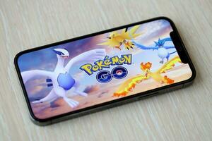 Pokemon partire mobile ios gioco su i phone 15 smartphone schermo su di legno tavolo durante mobile gameplay foto