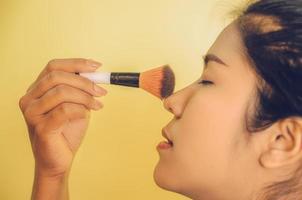 volto di bellezza della donna asiatica applicando i pennelli sulla pelle dai cosmetici. foto