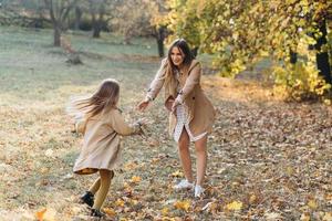 madre e figlia si divertono e camminano nel parco autunnale. foto