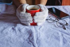 tazza di caffè rossa in mano indossando guanti in inverno foto