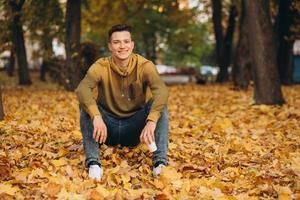 ragazzo bello e felice che sorride e sogna nel parco autunnale foto