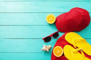 estate Accessori. Flip flop, occhiali da sole, asciugamano, rosso berretto e arance su blu di legno sfondo. copia spazio. foto