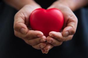 mani ravvicinate che danno cuore rosso come donatore di cuore foto